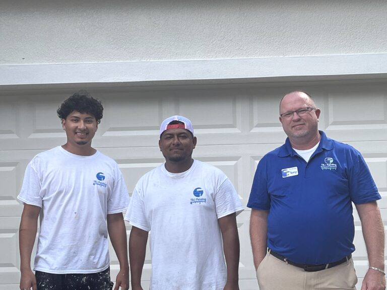 T&J Painting team members standing in front of a garage door